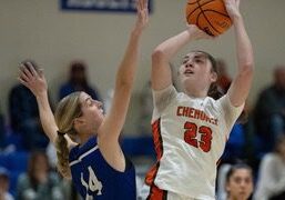 Female basketball player shooting over defender