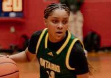 Focused player dribbling basketball in green jersey